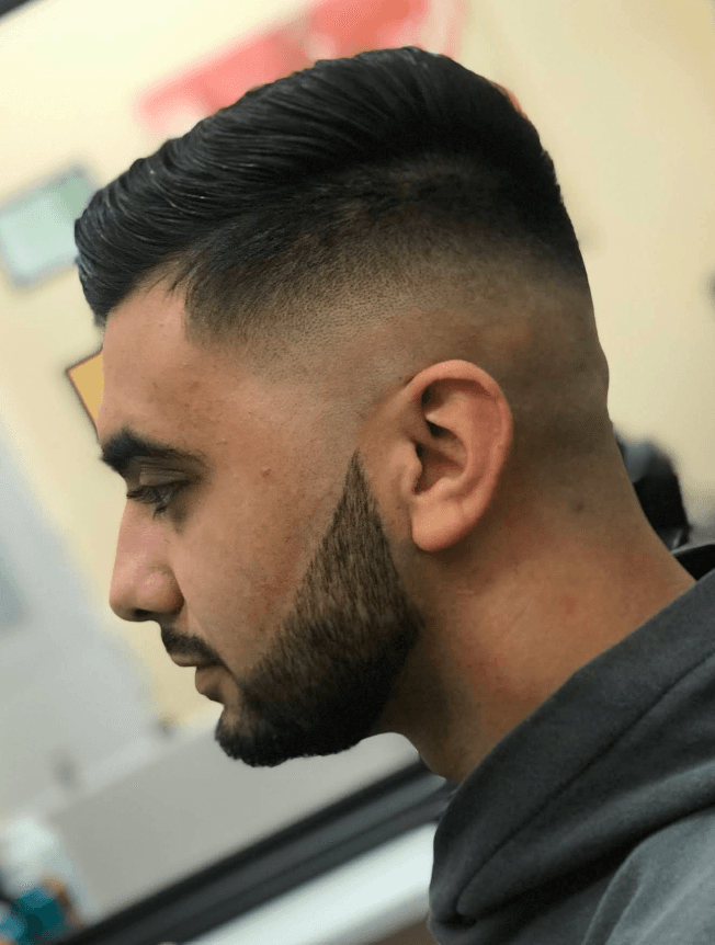 Skin fade with a sharp beard line and slicked-back finish